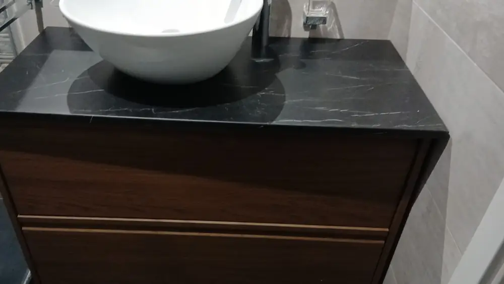 Mobile lavabo con piano in pietra e lavabo da appoggio, in un bagno rifatto.