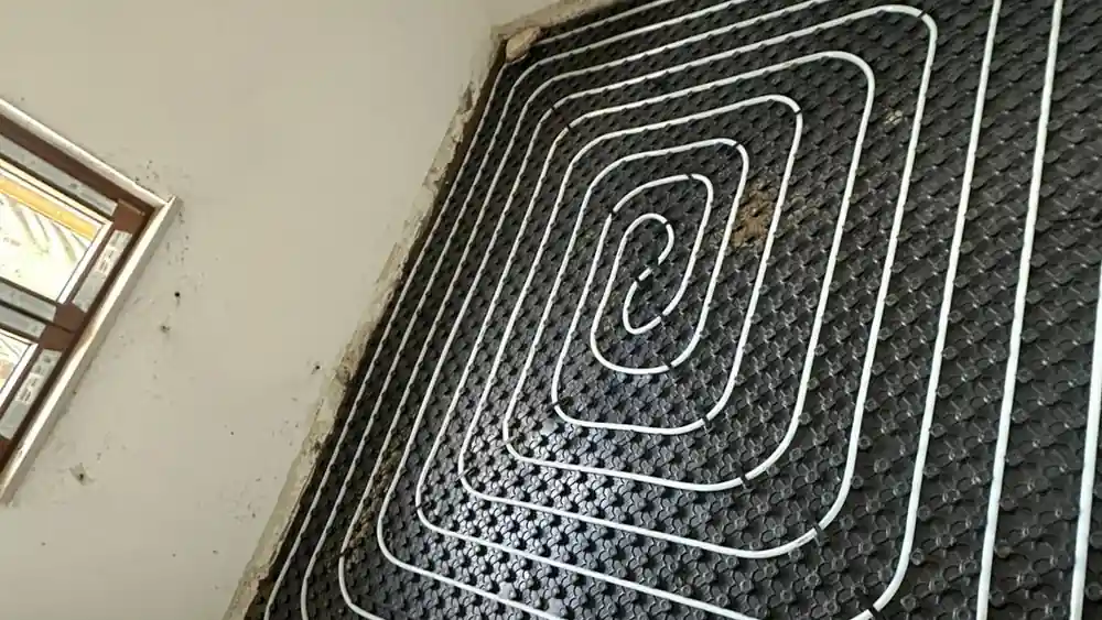 Underfloor heating being laid on a castellated panel, circuits across the whole floor area.